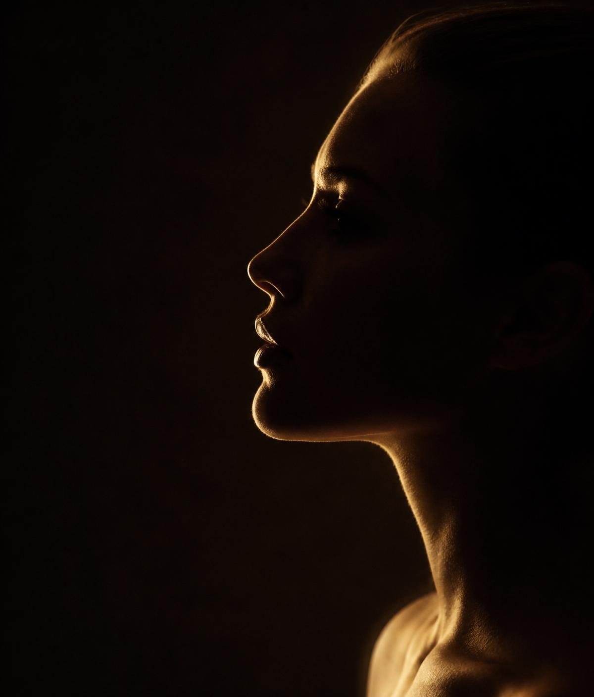 Perfil feminino em luz dourada representando harmonização facial